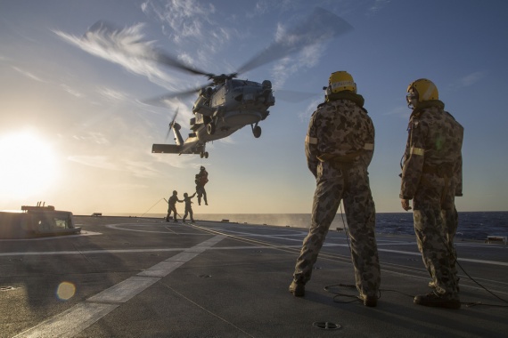 LSPT James Farquhar (left) and LSATV Dean Havelin marshal the embarked MH-60R Seahawk over the flight deck of HMAS Parramatta as it winches crew members aboard.