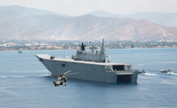 A MRH-90 Taipan helicopter delivers visitors from the Timor Leste government to HMAS Adelaide in Dili Harbour, as Navy and Army landing crafts depart to deploy a mobile hospital to Dili, Timor Leste, part of a Joint Task Group 661.1 response to a multi-national Humanitarian Assistance and Disaster Relief exercise.