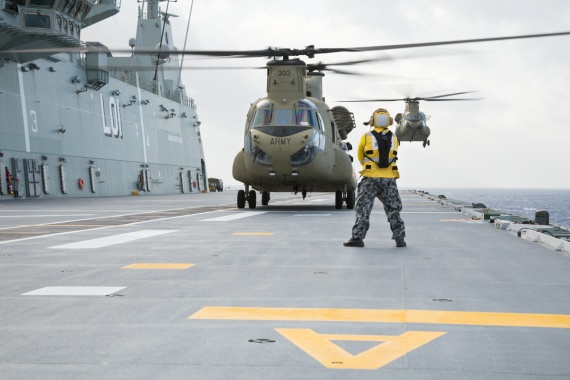 Leading Seaman Aviation Support Trent Gomm marshalls an Army CH-47F Chinook from C Squadron 5th Aviation Regiment, as another conducts a deck landing during training aboard HMAS Adelaide, off the east coast of Australia.