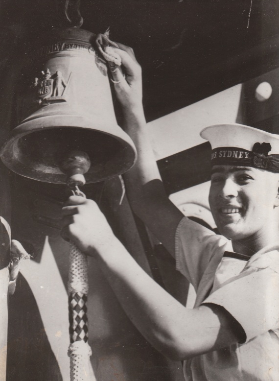 Able Seaman Alan Henry Oliver polishes the silver ship's bell onboard HMAS Sydney (II).