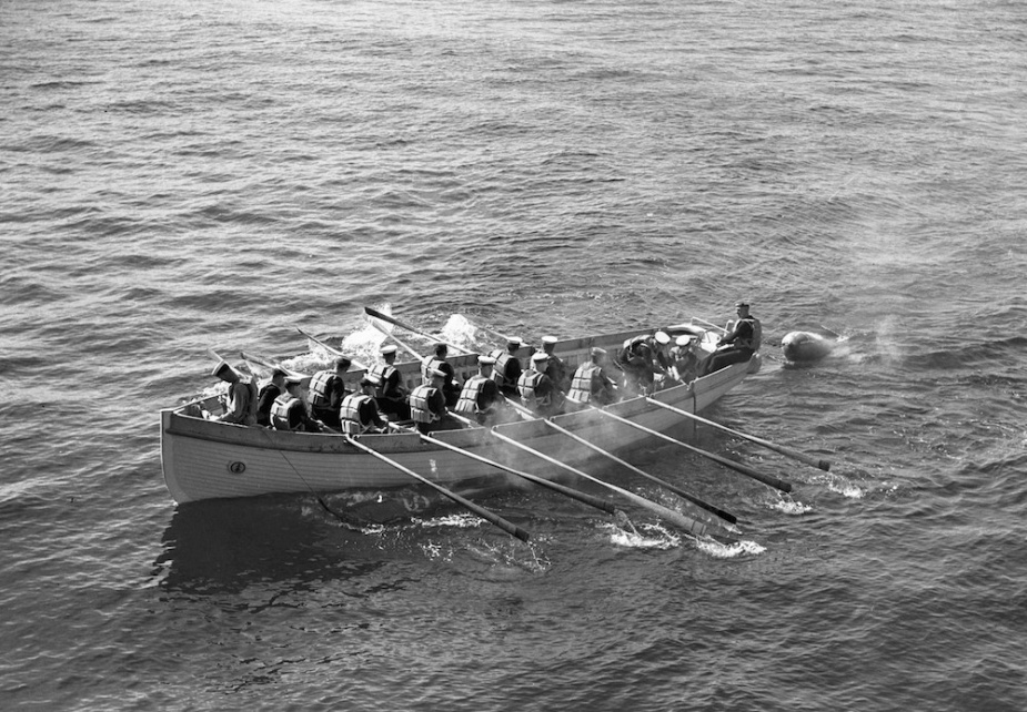 One of Sydney’s distinctive ‘clinker’ built cutters recovering a practice torpedo. Clinker built boats used planks that ran fore and aft with the lower edge of one plank lapping over the upper edge of the next below, like the slates on the roof of a house.