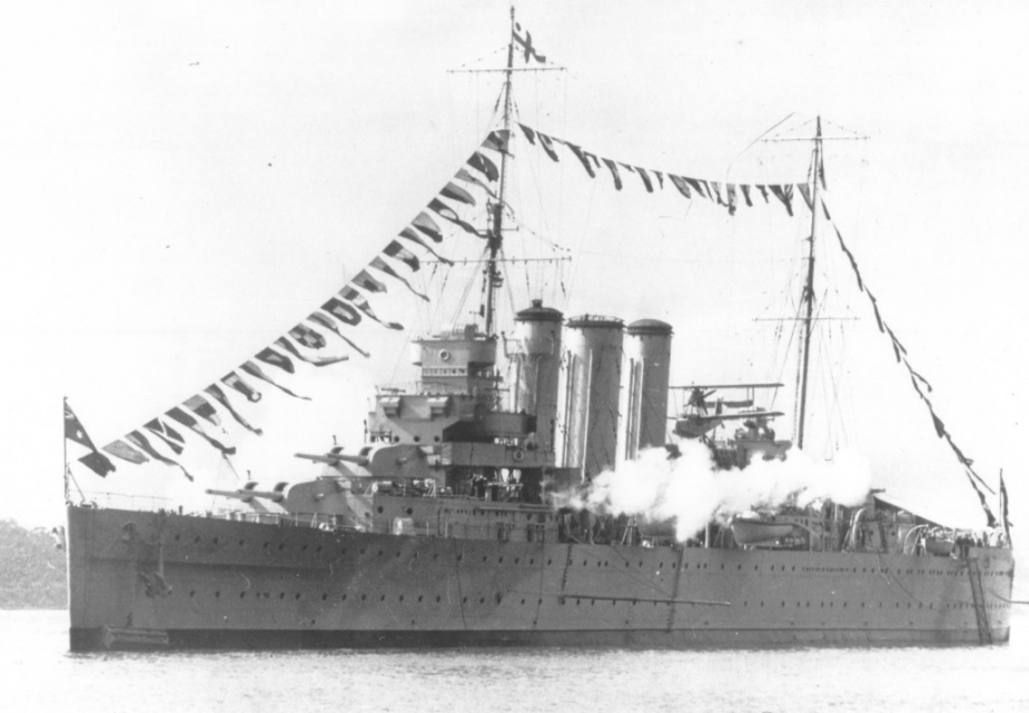 HMAS Canberra (I) dressed overall and firing a gun salute in Sydney Harbour, circa 1929.