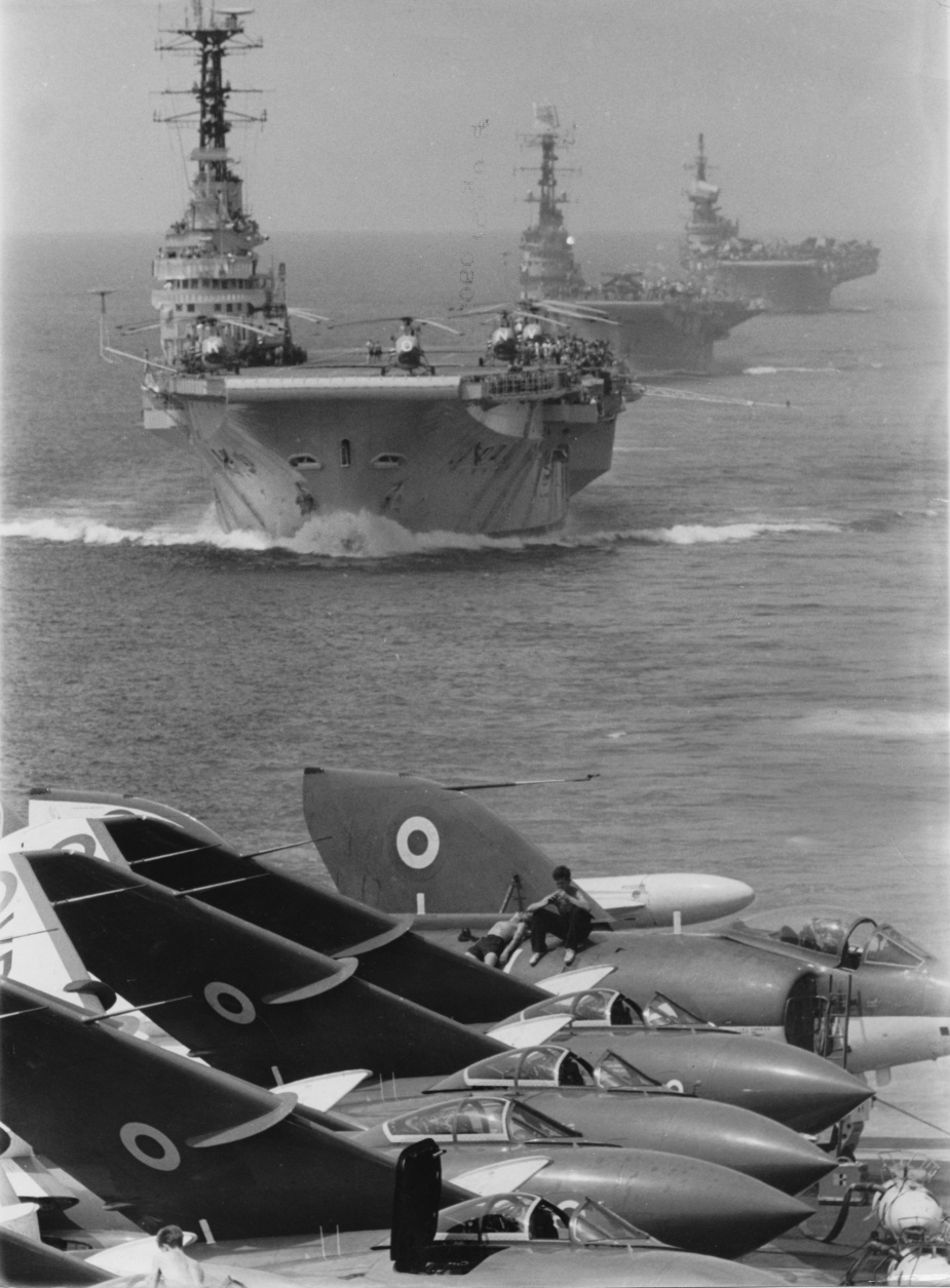 Exercise SHOWPIECE in the South China Sea. This photo is taken from the flight deck of the RN aircraft carrier HMS Eagle with her aircraft in the foreground. The three carriers astern of her are, from forward to rear, HMS Bulwark, HMAS Melbourne and HMS Victorious.