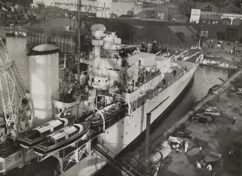 Sydney's seaplane crane visible mounted immediately behind her forward funnel. The crane's jib is in the raised position