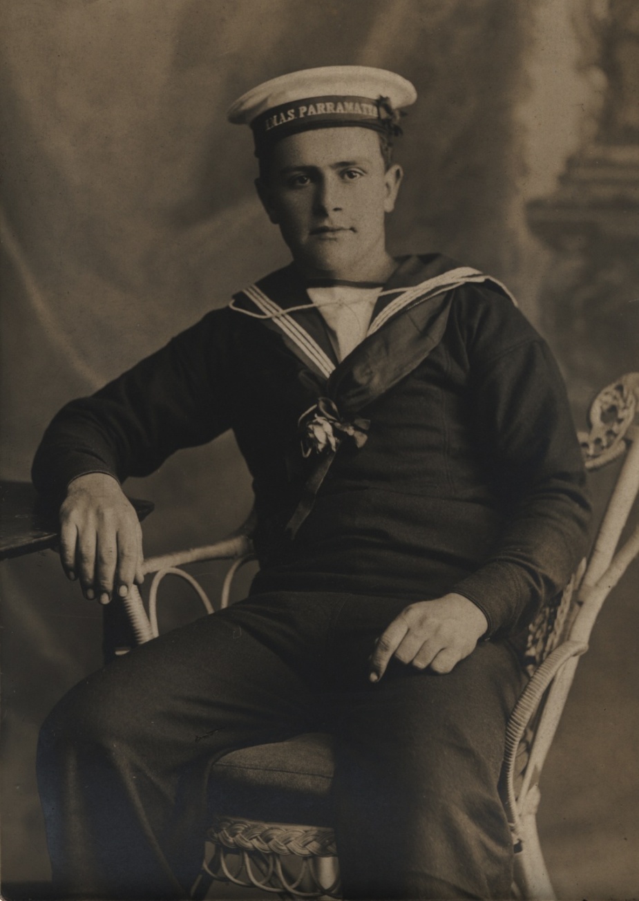 A seaman of HMAS Parramatta poses proudly in his uniform with cap ribbon clearly visible.