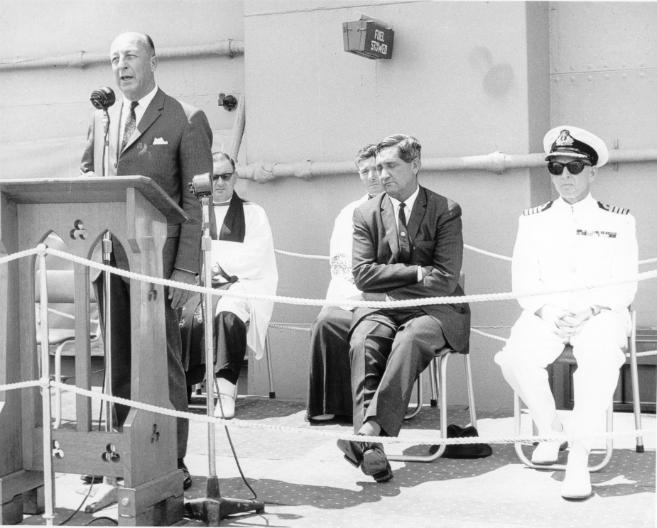 The Minister for Defence, the Hon Allen Fairhall, MP, addressing the audience at Melbourne's rededication ceremony on 14 February 1969. Behind him from left to right are Chaplain Alan Batt, Chaplain Louis Breslan, the Minister for the Navy, the Hon Charles 'Bert' Kelly, MP, and Melbourne's commanding officer, Captain John Stevenson, RAN.