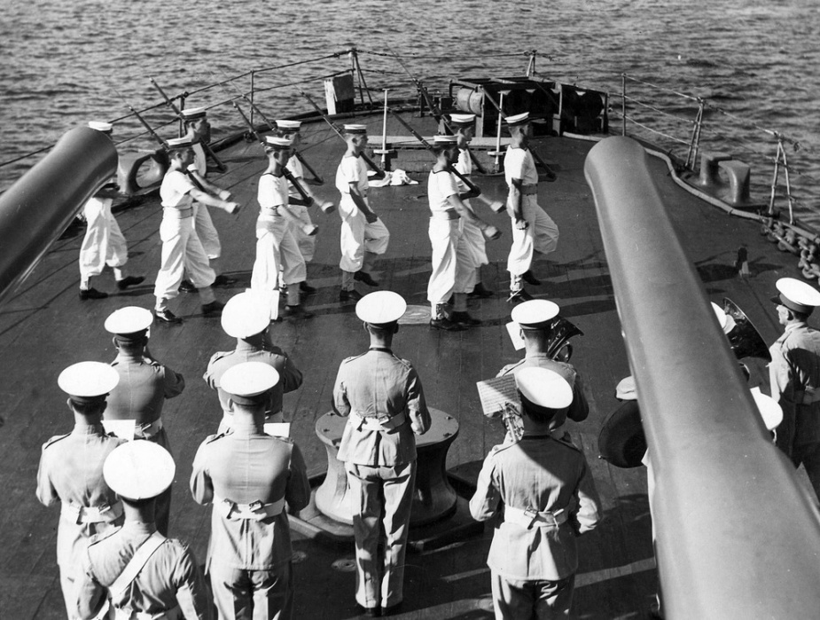 In this view of Sydney's quarterdeck can be seen several cylindrical smoke generators mounted vertically on her stern. To the right of them can be seen a depth charge rack holding several cylindrical charges mounted horizontally.