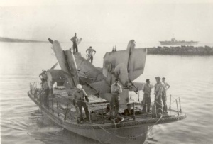 One of the RAN's new Fireflies being taken ashore by a lighter with HMAS Sydney in the background.