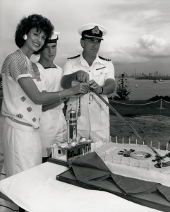 Miss Australia 1985 Maria Ridley joins HMAS Watson’s Commanding Officer Commander Ronald Cameron and Seaman Phillip Carley in cutting the cake to celebrate Watson’s 40th birthday.