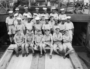 The Commanding Officer, Lieutenant Commander Charles Frederick Symonds, RN is in the centre of the front row. Note that a number of the crew are Melanesian.