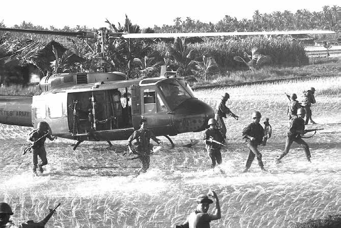 Troops leaving a Huey helicopter in a flooded rice field