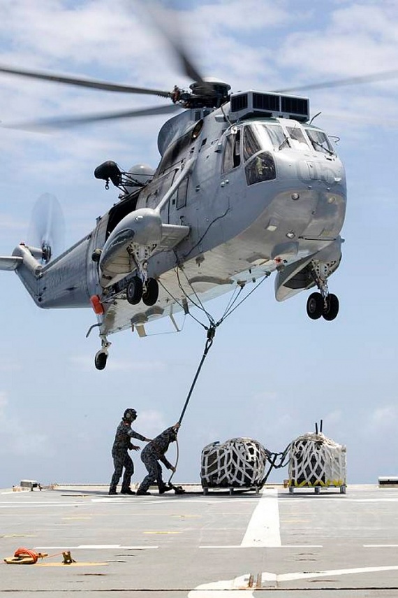 A Mk50A Sea King helicopter of 817 Squadron lifts a palletised load of musical instruments, belonging to the sea deployment group of the Royal Australian Navy Band, for transfer from HMAS Kanimbla to the USS Cleveland. The Band are cross decking to USS Cleveland and USS Bon Homme Richard to provide entertainment to US Marines and sailors, and Australian Regular Army soldiers embarked on the two ships.