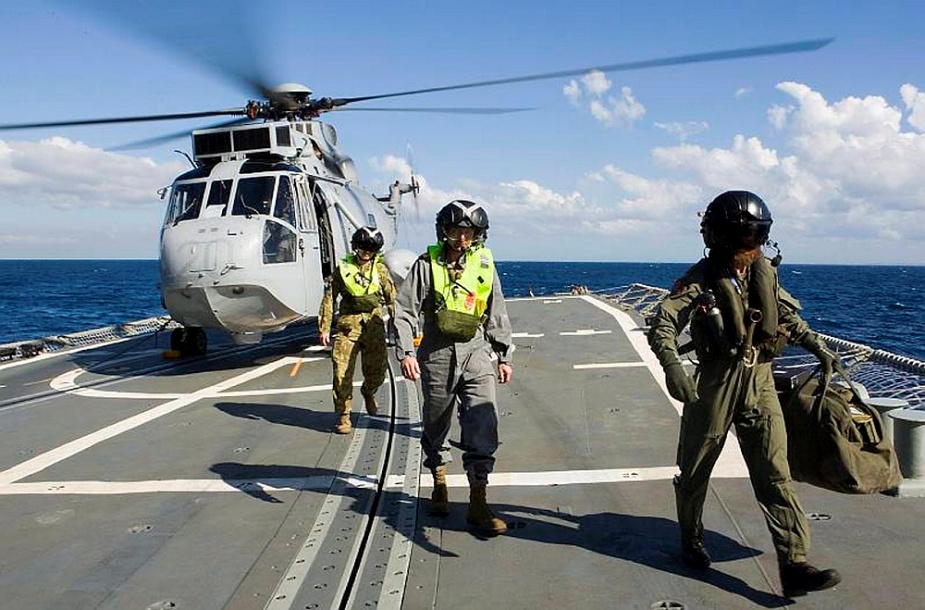 Rear Admiral Peter D. Jones, DSC, AM, RAN, Head of Information and Communications Technology Operations and Strategic J6 within the Chief Information Officer Group (CIOG) is escorted from HMAS Kanimbla's Seaking across the flight deck of HMAS Darwin.