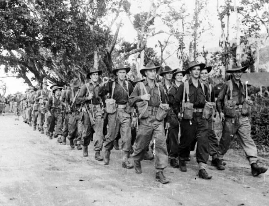 Members of the 6th Australian Division marching to the beachhead of But Beach, New Guinea to board HMAS Colac and her sister ship HMAS Dubbo in preparation for the amphibious assault on the Wewak Peninsula, circa May 1945. (AWM 018495)