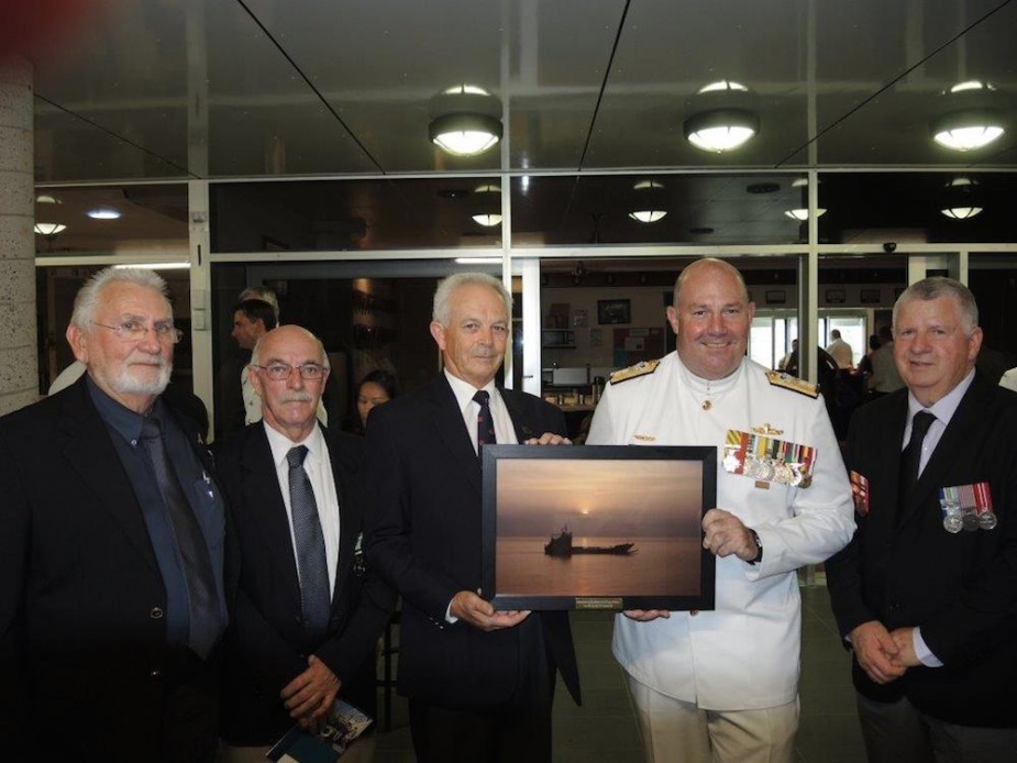 Members of HMAS Labuan’s Commissioning Crew present the Fleet Commander with a framed sunset photo of HMAS Brunei, commemorating the sun setting on the LCH era in the RAN, 19 November 2014. From left: Larry Ogden, Bob Davis, Wayne Ferguson, Rear Admiral Stuart Mayer, CSC*, RAN and Bruce McCoist. (Wayne Ferguson collection)