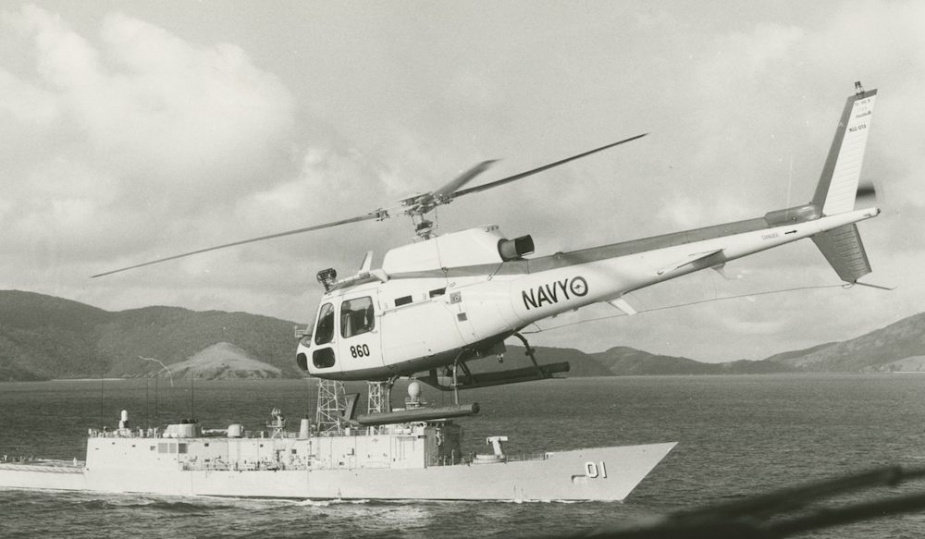 A 723 Squadron Squirrel flies past an Adelaide Class guided missile frigate HMAS Adelaide.